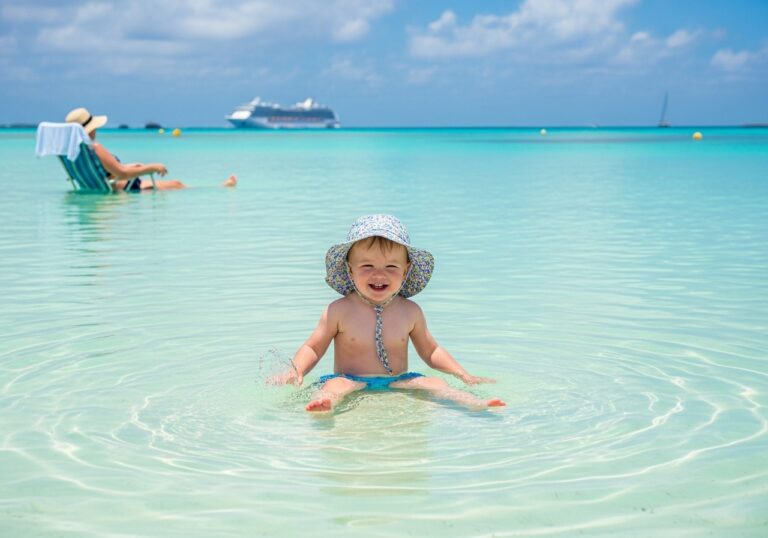 A toddler splashing safely in calm water at one of the best caribbean cruise ports for toddlers.